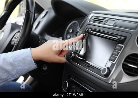 Scelta della radio preferita. Donna che preme il pulsante sull'audio del veicolo in auto, primo piano Foto Stock