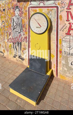 Ouarzazate, Marocco - 15 ottobre 2023: Bilancia d'epoca su un marciapiede con un murale di Charlie Chaplin Foto Stock