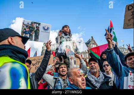 Amsterdam, Paesi Bassi. 15 ottobre 2023. Una bambina osserva i discorsi sulle spalle del padre durante una manifestazione di solidarietà con la Palestina. La comunità palestinese nei Paesi Bassi ha organizzato una marcia nel centro della città per condannare il governo di Israele ed esprimere solidarietà al popolo palestinese. Credito: SOPA Images Limited/Alamy Live News Foto Stock