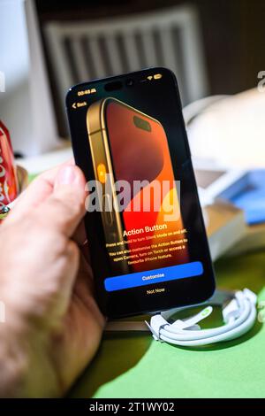 Londra, Regno Unito - 25 settembre 2023: Uomo che configura il pulsante azione sul suo nuovo iPhone 15 Pro in titanio, scattato dal suo punto di vista in una stanza creativa Foto Stock