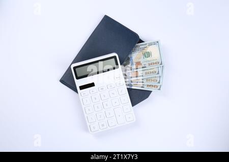 Calcolatrice, banconote in dollari e portafoglio su sfondo bianco, vista dall'alto. Concetto di pensionamento Foto Stock