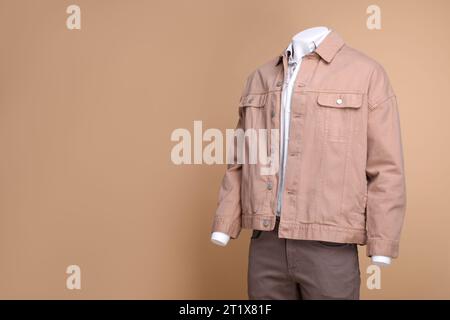 Manichino maschile vestito con camicia bianca, giacca e pantaloni su sfondo beige, spazio per il testo Foto Stock