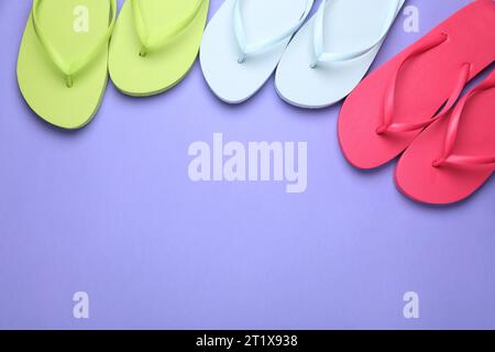 Molte infradito diverse su sfondo viola chiaro, piatto. Spazio per il testo Foto Stock