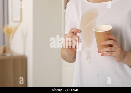 Donna che mostra macchie di caffè sulla camicia al chiuso, primo piano. Spazio per il testo Foto Stock