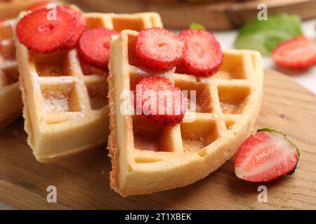 Gustosi waffle belgi con fragole e zucchero in polvere su tavola di legno, primo piano Foto Stock