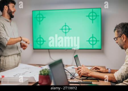 Professionisti aziendali che collaborano su progetti architettonici in una sala riunioni multiculturale Foto Stock