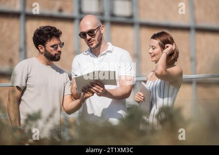 Un gruppo di architetti che discutono di un progetto per un edificio moderno. Collaborazione e lavoro di squadra per un design urbano di successo. Foto Stock