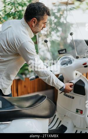 Elegante uomo di mezza età che arriva e lascia Workspace dopo il lavoro in motocicletta Foto Stock