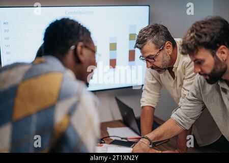 Diversi professionisti discutono di progetti architettonici, grafici e statistiche in una riunione aziendale produttiva, per far progredire l'azienda. Foto Stock