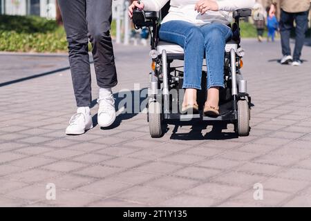 donna che usa una sedia a rotelle con un uomo che fa una passeggiata Foto Stock