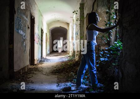 Un modello femminile si pone all'interno delle rovine di una base militare dell'epoca sovietica a Szombatheley, in Ungheria. Foto Stock