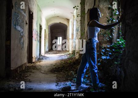 Un modello femminile si pone all'interno delle rovine di una base militare dell'epoca sovietica a Szombatheley, in Ungheria. Foto Stock