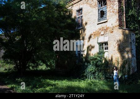 Un modello femminile si pone all'interno delle rovine di una base militare dell'epoca sovietica a Szombatheley, in Ungheria. Foto Stock