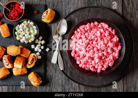 insalata cremosa di mirtilli rossi con mini marshmallow, mela fresca e noci pecan in ciotola nera su tavolo di legno scuro con panini alla cannella, ricetta americana, ho Foto Stock
