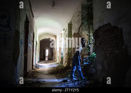 Un modello femminile si pone all'interno delle rovine di una base militare dell'epoca sovietica a Szombatheley, in Ungheria. Foto Stock