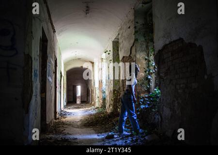 Un modello femminile si pone all'interno delle rovine di una base militare dell'epoca sovietica a Szombatheley, in Ungheria. Foto Stock