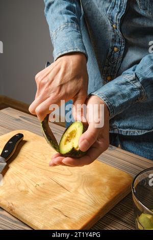 Primo piano delle mani femminili che prendono la polpa di avocado con il cucchiaio Foto Stock