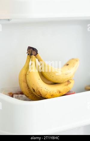 Primo piano delle banane sullo scaffale nel contenitore aperto del frigorifero. Foto Stock