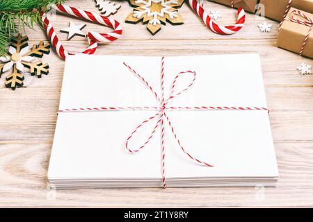 Busta con foglio di carta bianco su sfondo di Natale - ramo di abete, pigne, nastro rosso, stella e il cuore di dolci. Spazio per il testo. Tonica. Foto Stock