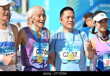 (231016) -- TIANJIN, 16 ottobre 2023 (Xinhua) -- Liu Runlong (2nd L) posa insieme ad altri runner per una foto di gruppo dopo la maratona di Tianjin del 2023, a Tianjin del nord della Cina, il 15 ottobre 2023. Liu Runlong, 72 anni, è un appassionato di maratona. Ha partecipato alla prima maratona tenutasi a Tianjin nel 1981. Liu ha perso la mano destra in un incidente sul lavoro nel 1996. La disabilità fisica non gli ha impedito di correre. Liu ha partecipato a molte gare di maratona a Pechino, Dalian, Xiamen e in altre città della Cina. Ogni mattina alle quattro, Liu iniziò a correre lungo il fiume Haihe. Correrò il più a lungo possibile. Ma Foto Stock