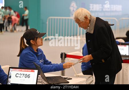 (231016) -- TIANJIN, 16 ottobre 2023 (Xinhua) -- Liu Runlong (R) riceve le forniture di 2023 Tianjin Marathon, al Meijiang Convention and Exhibition Center nel nord della Cina, Tianjin, il 12 ottobre 2023. Liu Runlong, 72 anni, è un appassionato di maratona. Ha partecipato alla prima maratona tenutasi a Tianjin nel 1981. Liu ha perso la mano destra in un incidente sul lavoro nel 1996. La disabilità fisica non gli ha impedito di correre. Liu ha partecipato a molte gare di maratona a Pechino, Dalian, Xiamen e in altre città della Cina. Ogni mattina alle quattro, Liu iniziò a correre lungo il fiume Haihe. 'Correrò così a lungo Foto Stock