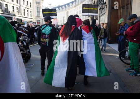 Londra, Regno Unito. 14 ottobre 2023. I manifestanti avvolti da bandiere palestinesi camminano lungo Regent Street durante una "marcia per la Palestina”, come parte di una manifestazione nazionale pro-palestinese. La marcia è stata organizzata da Palestine Solidarity Campaign, Friends of al-Aqsa, Stop the War Coalition, Muslim Association of Britain, Palestinian Forum in Britain e CND. (Foto di Tejas Sandhu/SOPA Images/Sipa USA) credito: SIPA USA/Alamy Live News Foto Stock