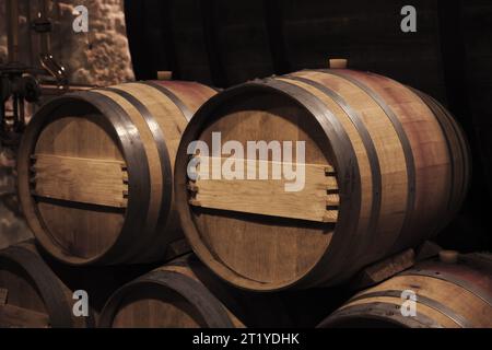 Botti di legno di quercia all'interno di una cantina scura, foto ravvicinata con messa a fuoco selettiva Foto Stock