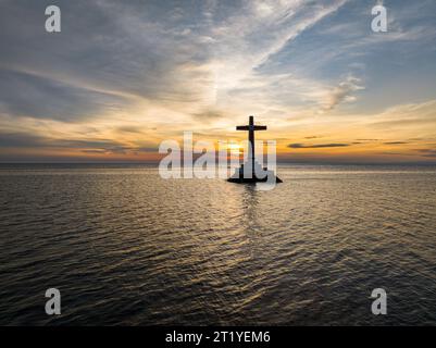 Sfondo del tramonto su una grande croce del Cimitero sommerso sull'isola di Camiguin. Filippine. Foto Stock