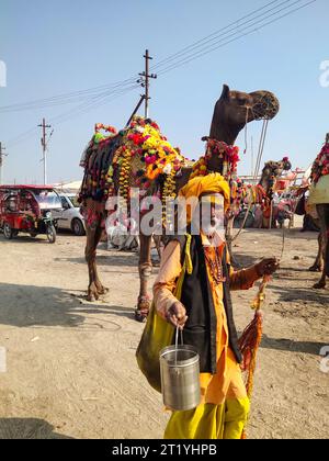 PRAYAGRAJ, UTTAR PRADESH, INDIA - 14 AGOSTO 2023: Uomo indiano e cammello all'alba. Foto Stock