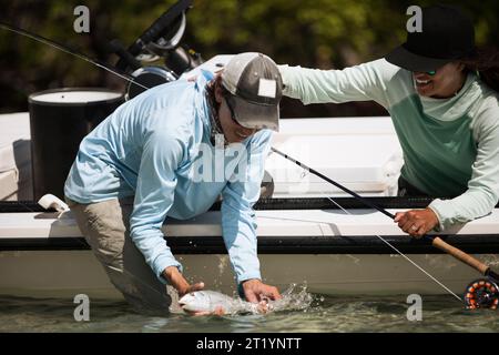 Pescatore che tiene il pesce bonefish in acqua Foto Stock