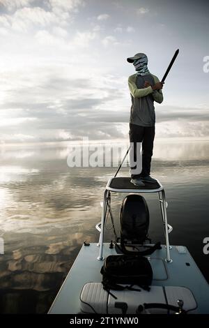 Uomo con bastone in piedi sul motoscafo Foto Stock