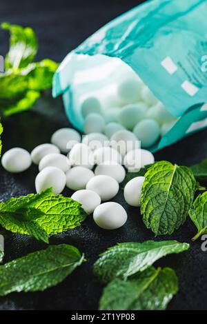 Caramelle alla menta. Ossa di mentolo e foglie di menta sul tavolo nero. Foto Stock