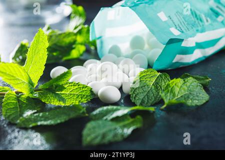 Caramelle alla menta. Ossa di mentolo e foglie di menta sul tavolo nero. Foto Stock