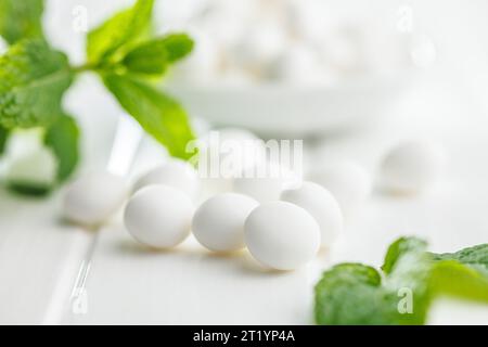 Caramelle alla menta. Ossa di mentolo e foglie di menta sul tavolo bianco. Foto Stock