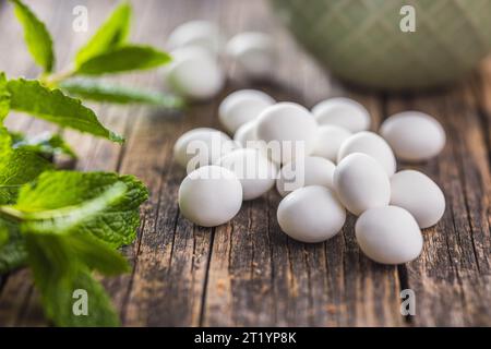 Caramelle alla menta. Bonboni di mentolo e foglie di menta sul tavolo di legno. Foto Stock