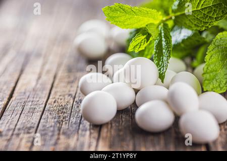 Caramelle alla menta. Bonboni di mentolo e foglie di menta sul tavolo di legno. Foto Stock