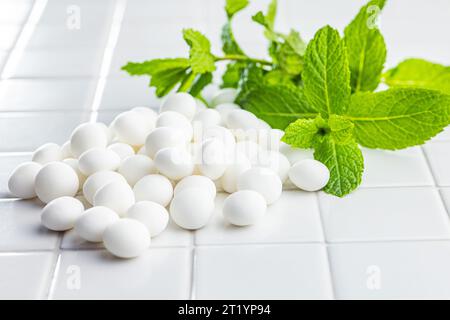 Caramelle alla menta. Ossa di mentolo e foglie di menta sul tavolo bianco. Foto Stock