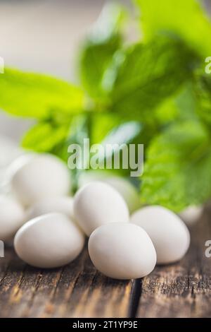 Caramelle alla menta. Bonboni di mentolo e foglie di menta sul tavolo di legno. Foto Stock