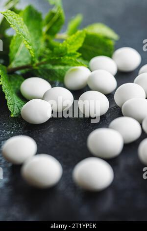 Caramelle alla menta. Ossa di mentolo e foglie di menta sul tavolo nero. Foto Stock