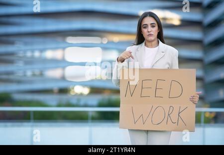 La donna con un cartello di carta ha bisogno di un lavoro che sembri sconvolta all'aperto Foto Stock