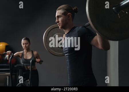 Giovane coppia sportiva caucasica che lavora insieme in palestra. Formazione di gruppo sui circuiti funzionali con attrezzatura crossfit. Uomini e donne che si allenano al club sportivo Foto Stock