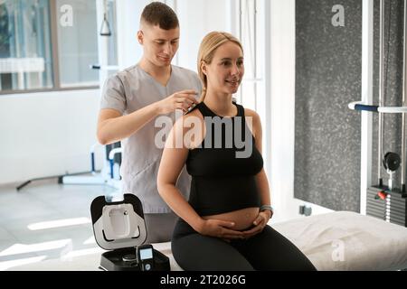 Il giovane specialista in un centro benessere utilizza la terapia hardware Foto Stock