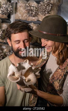 felice coppia contadina che tiene funghi ostriche in fattoria funghi Foto Stock