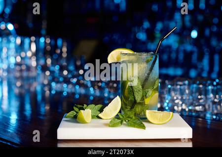 sofisticato e ghiacciato cocktail mojito con foglie di menta e lime sullo sfondo del bar Foto Stock