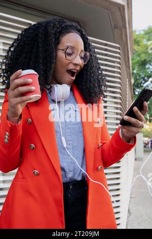 donna d'affari con fotografia verticale che riceve buone notizie sul telefono cellulare. Foto Stock