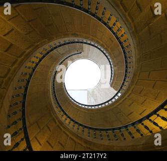 Vista da sotto di una scala a chiocciola verso l'infinito, in pietra. Architettura antica, scala, circolazione, vista verso l'alto. spir molto particolare Foto Stock