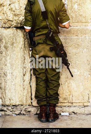 Schiena di una saldatrice israeliana non identificabile che prega sul muro occidentale del pianto a Gerusalemme, Israele. Israele sta attualmente combattendo una guerra contro Hamas Foto Stock