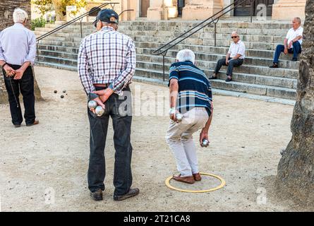 Uomini più anziani che giocano a Petanque in una piazza della città Foto Stock