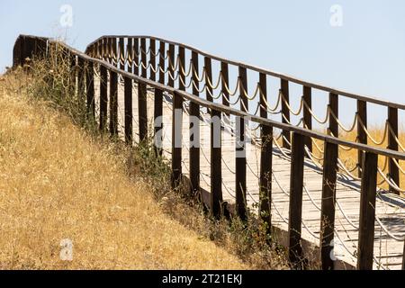 Ponte di recinzione in legno sul prato e sull'erba. Fatto di funi. Percorso del marciapiede Foto Stock