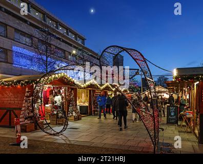 Le luci natalizie aggiungono calore alle piccole bancarelle di legno del mercatino di Natale di Plymouth dopo il tramonto del 2021 Foto Stock